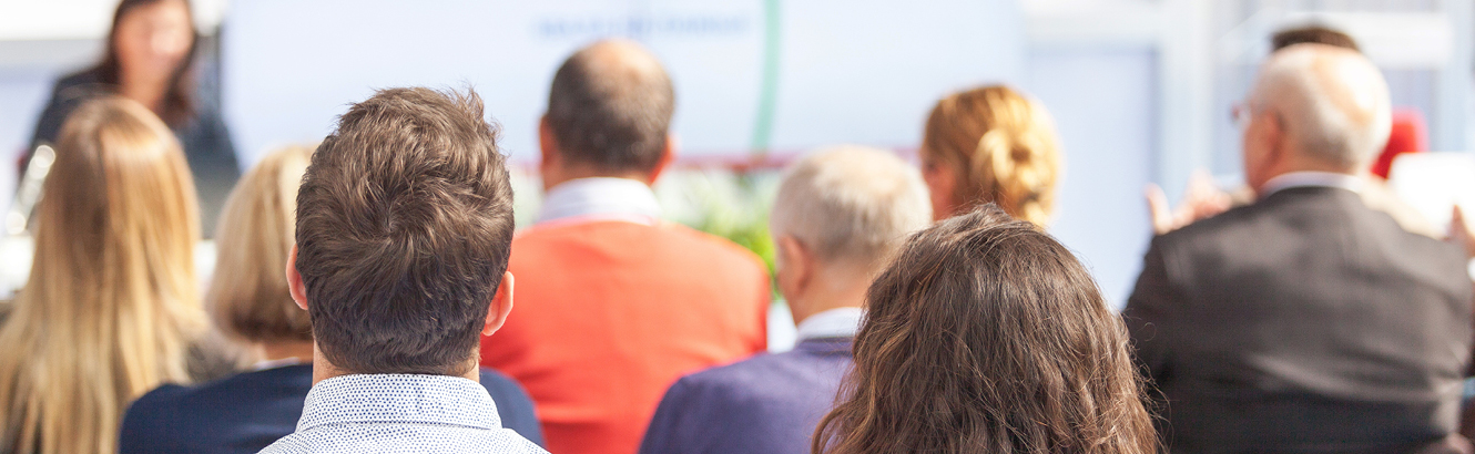 Various people sitting and listening to a speaker.